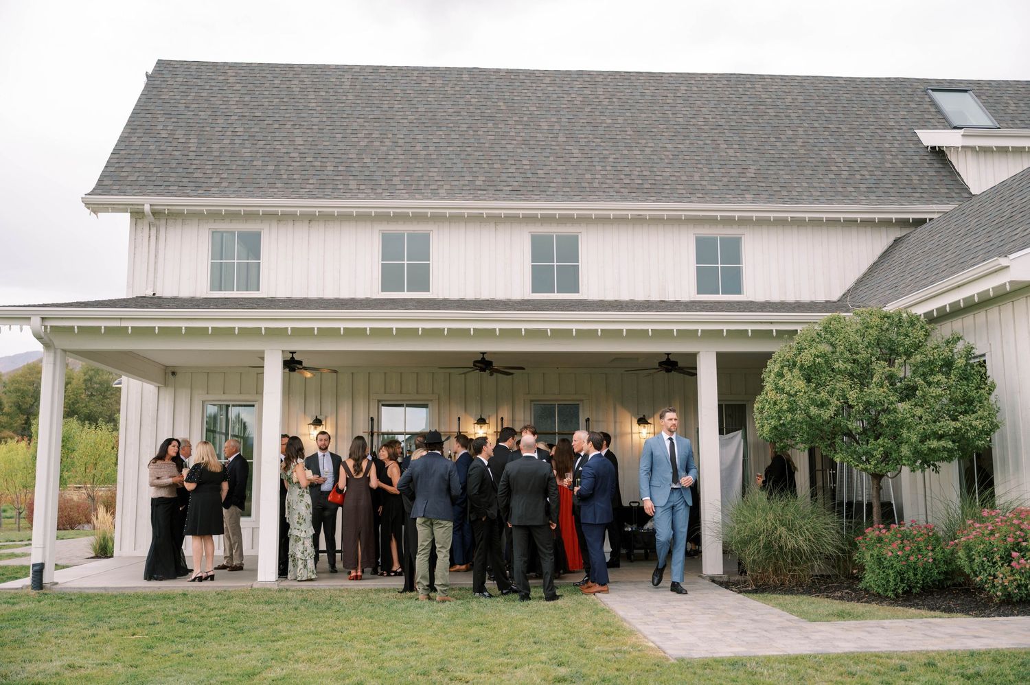 A panoramic view shows a group of people gathered outside a white residential building.