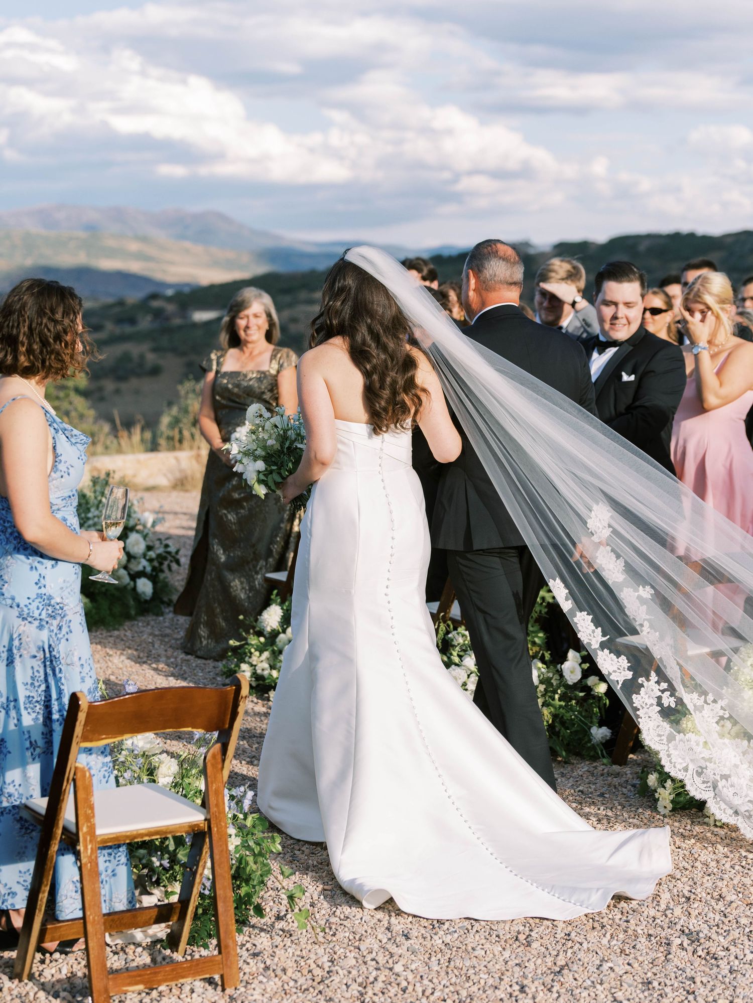 Wedding ceremony setup with guests gathering in scenic mountain location.