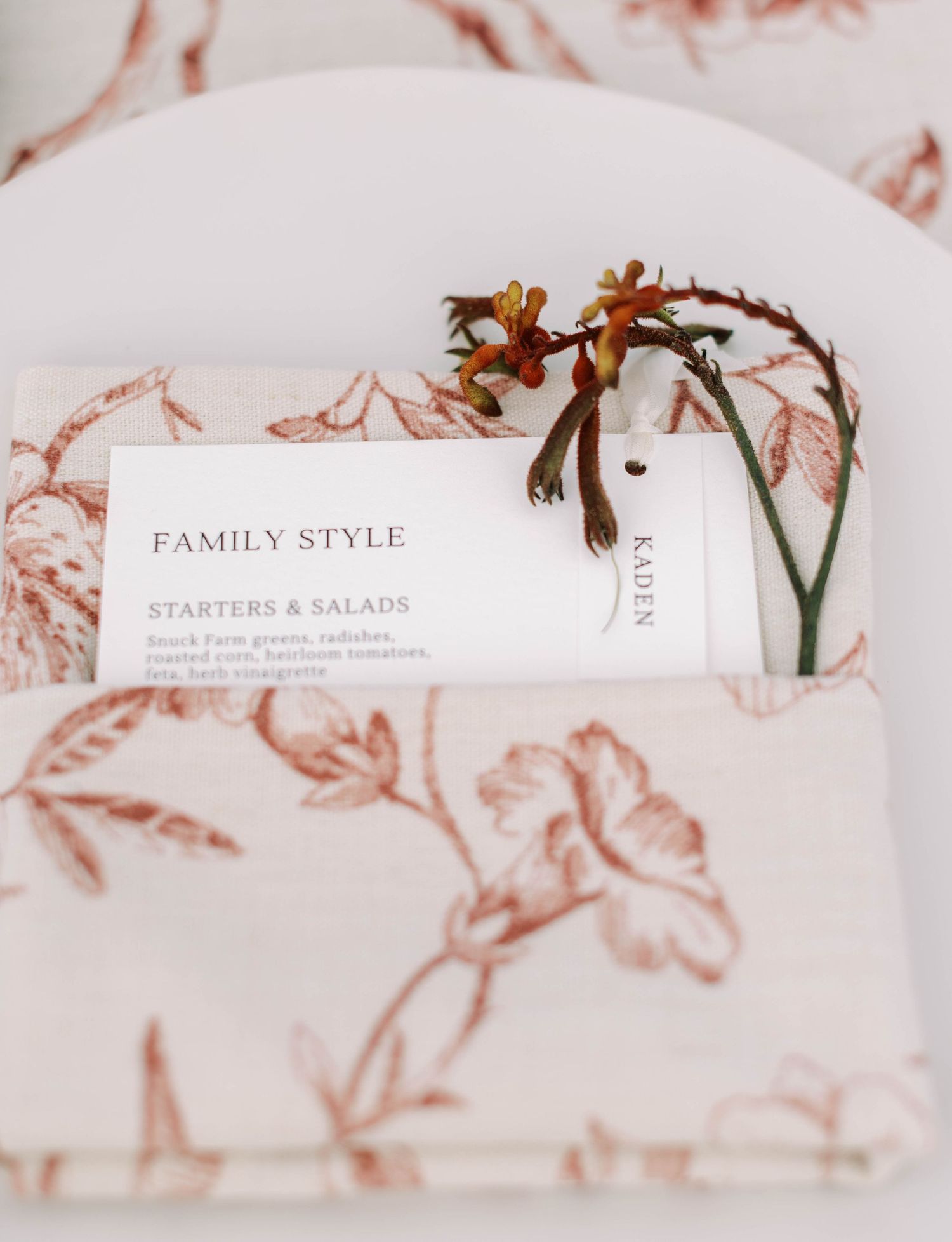 Elegant wedding stationery with soft pink floral designs and delicate calligraphy text laid out in a romantic arrangement.