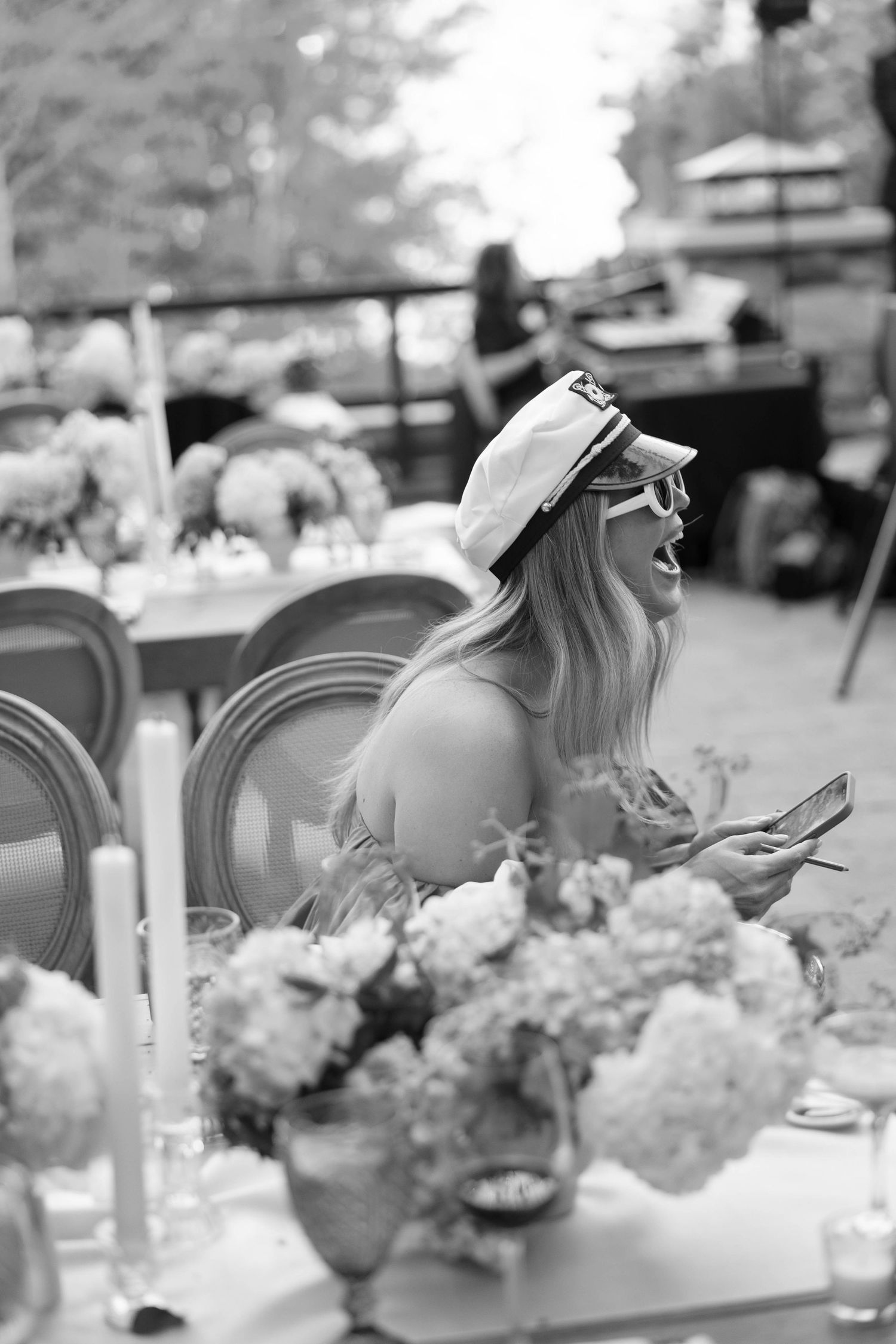 Black and white photo sequence of a guest in a sun hat laughing during an elegant outdoor reception.