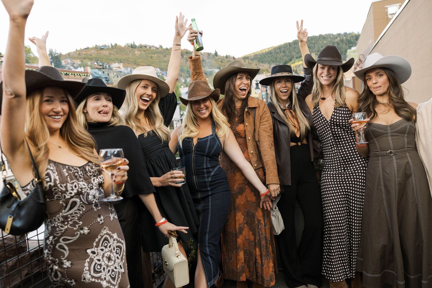 Group of people celebrating outdoors with drinks and cowboy hats at a western-themed gathering.