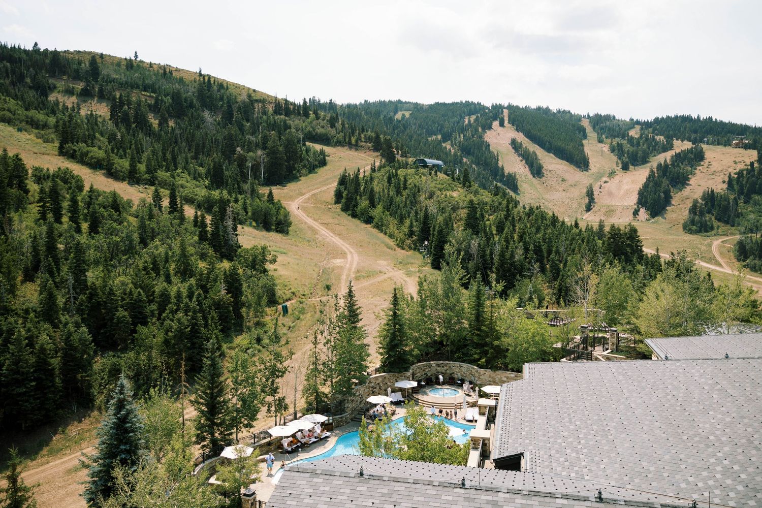 Panoramic view of ski slopes and chairlifts on a forested mountain during summer season at a ski resort.