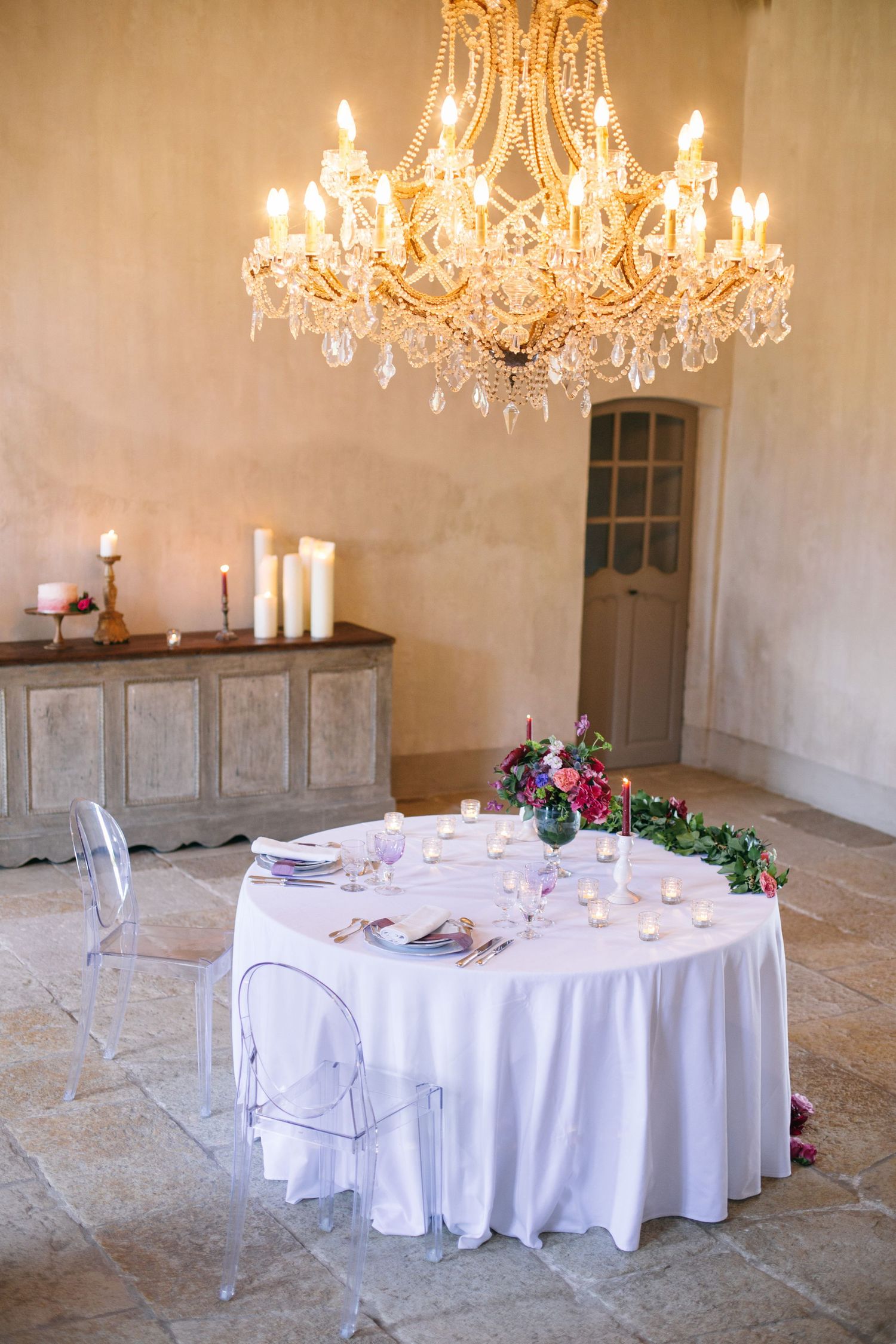 Romantic table setting under crystal chandelier with white tablecloth and floral centerpiece at chateau de moissac.
