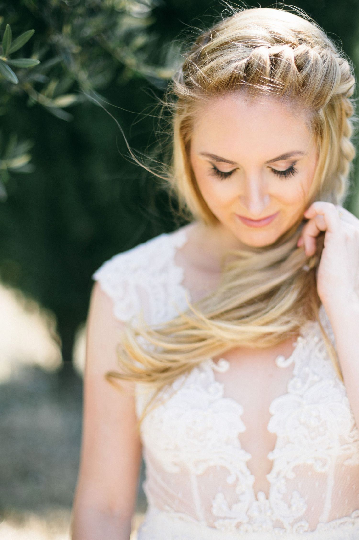 Romantic bridal portrait featuring delicate lace dress against green foliage of berta bridal gown.
