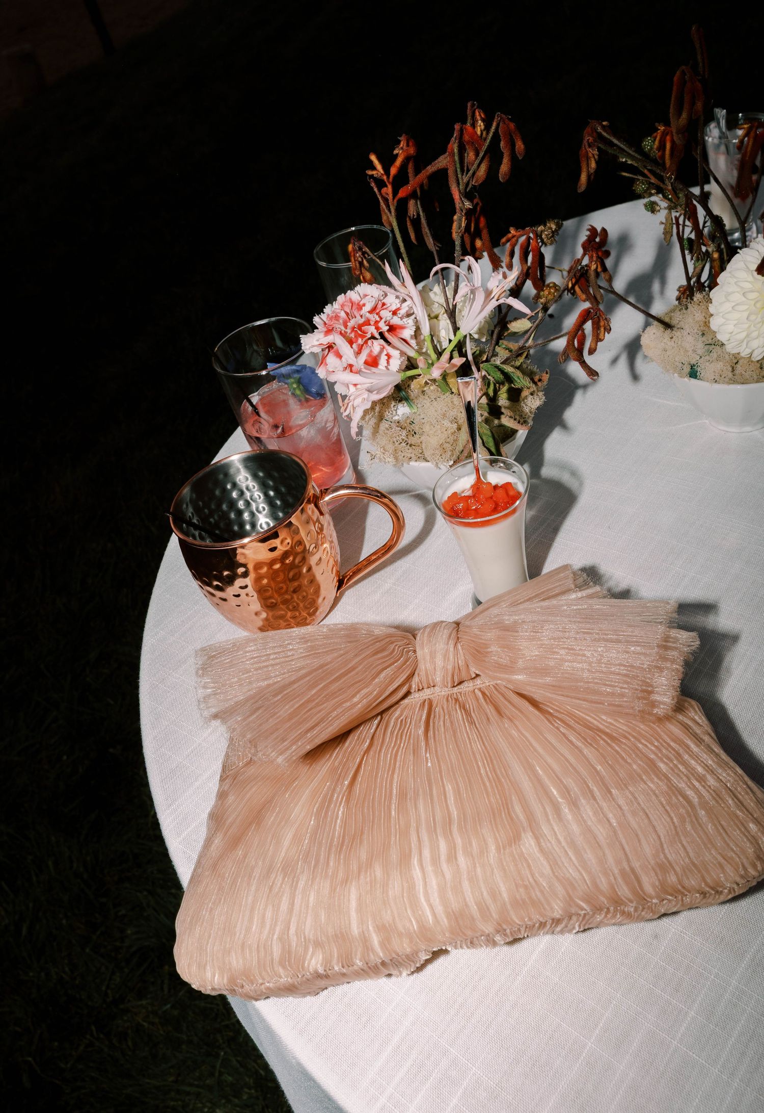 A peach-colored pleated tablecloth drapes elegantly across a surface with decorative floral arrangements visible.