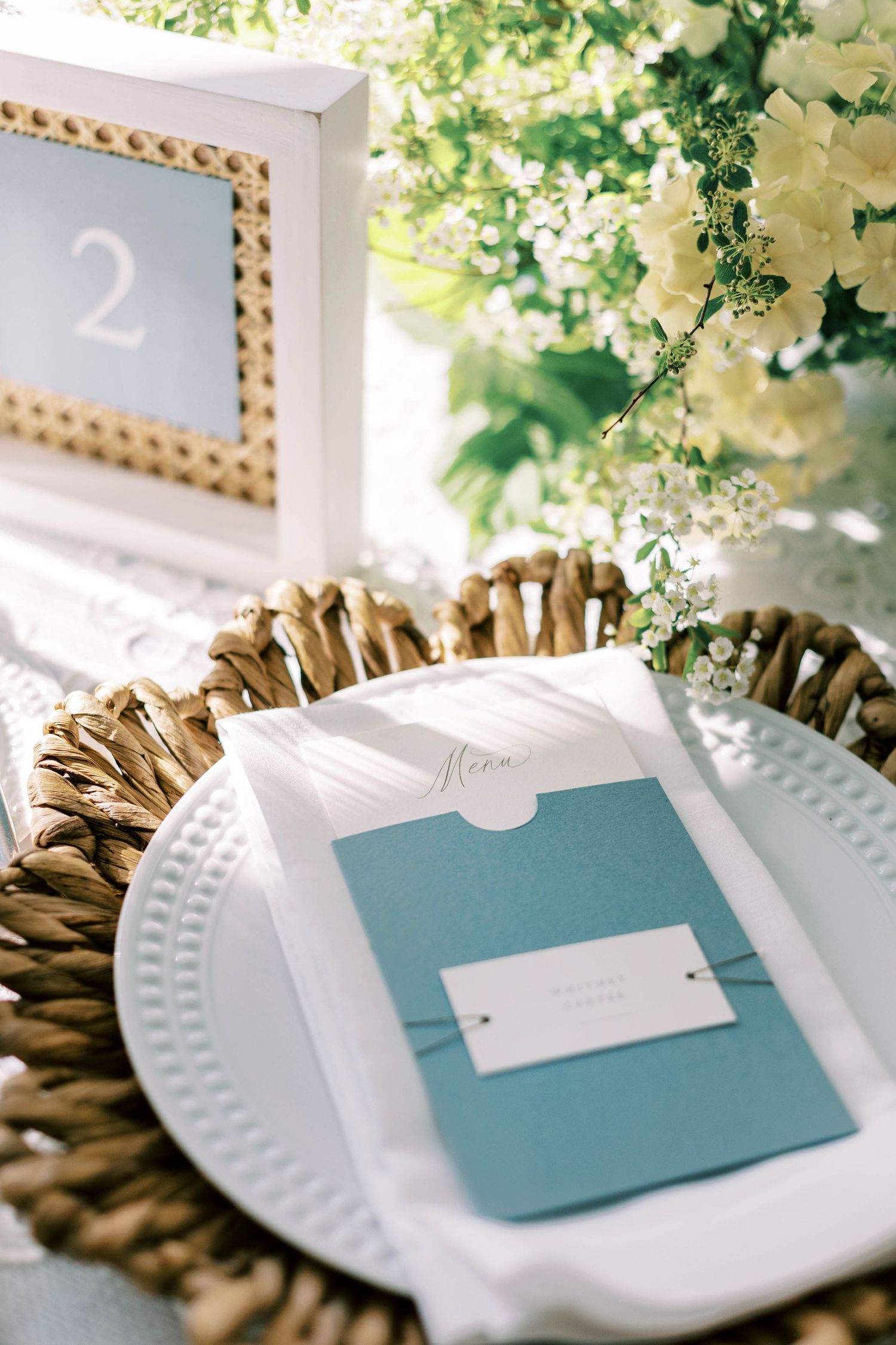 Table number and place setting with blue menu card in gold frame at wedding reception at everline resort lake tahoe.