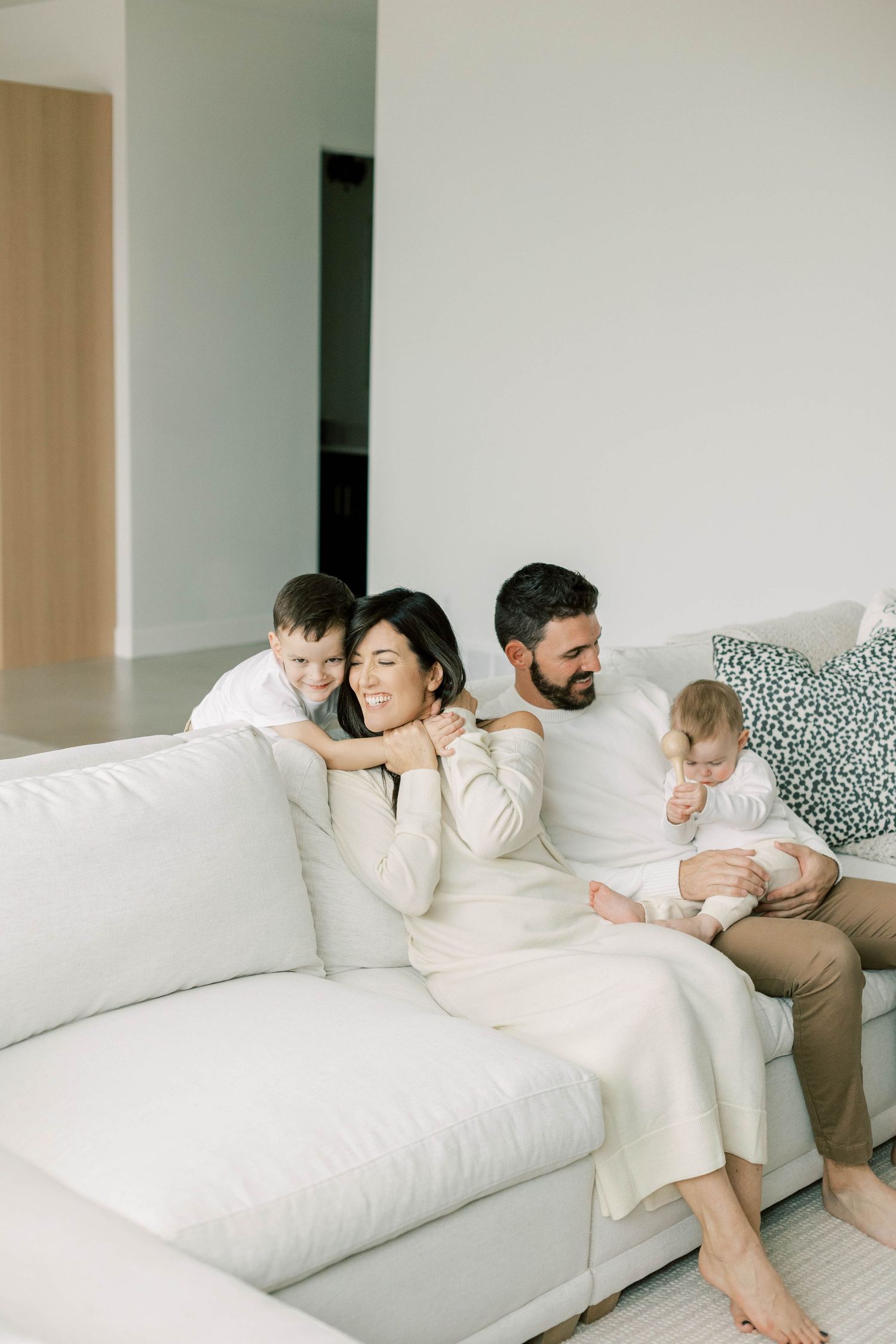 Family sharing loving moment on white sofa in bright contemporary living space.