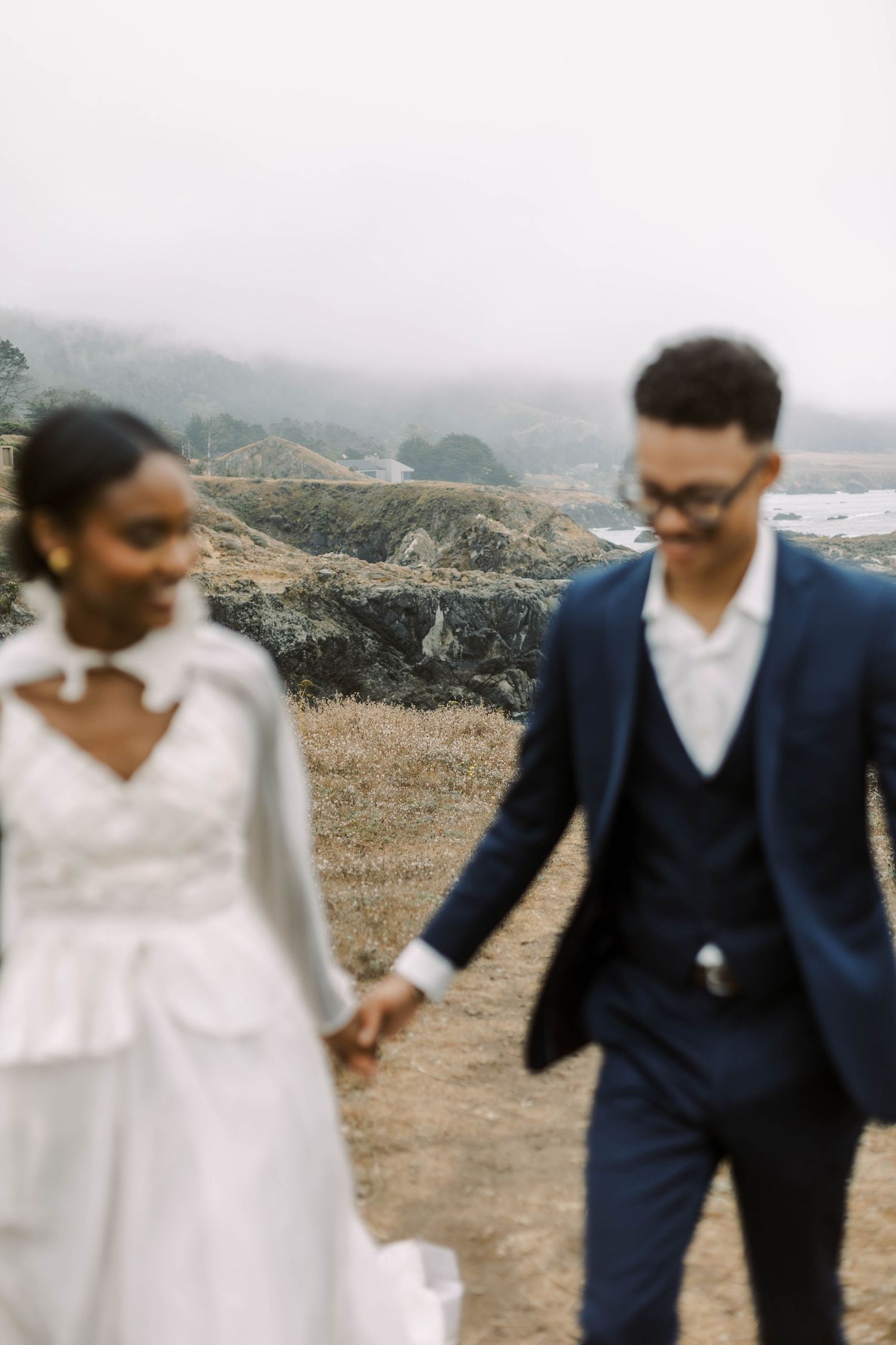 Couple holding hands and walking together on a scenic mountain ridge.