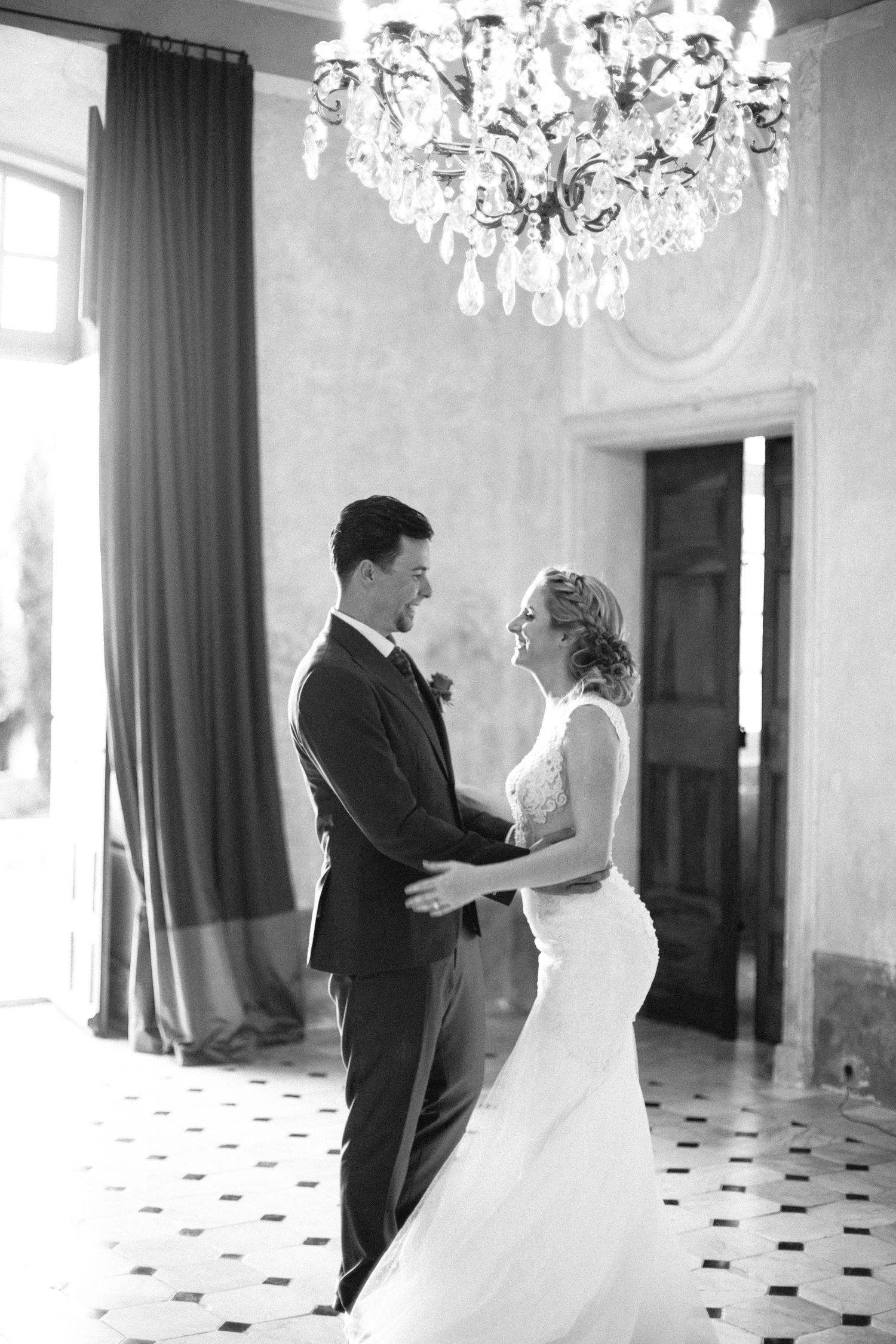 Romantic wedding couple dancing beneath an ornate crystal chandelier in an elegant ballroom at chateau de moissac.