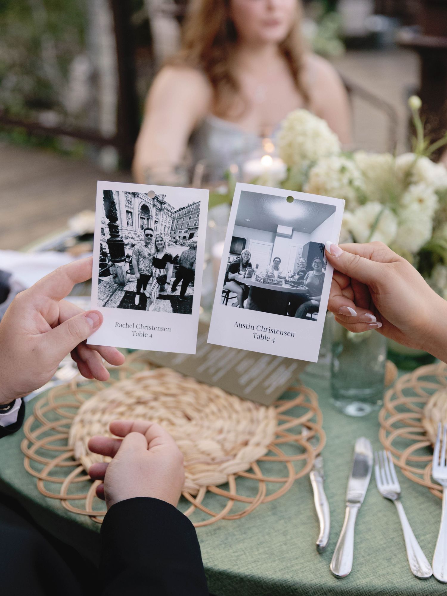 Wedding guests looking at vintage black and white photographs displayed on woven placemats at reception tables.