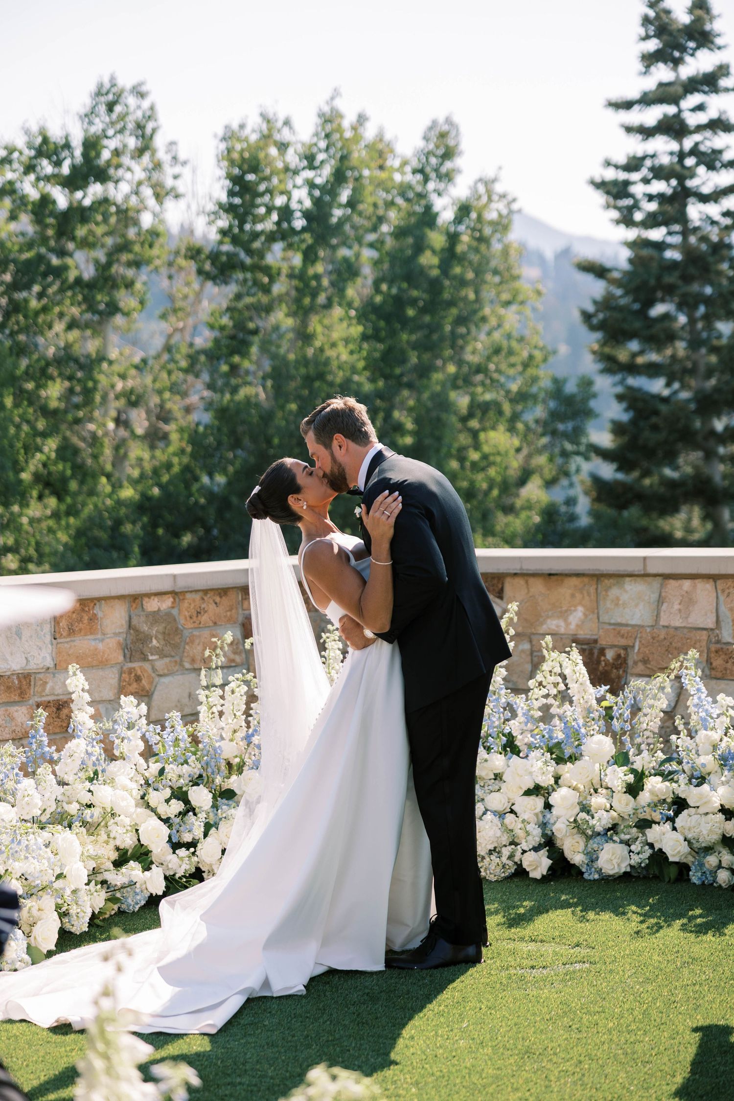 Elegant outdoor wedding ceremony setup with white floral arrangements and mountain views in the background.