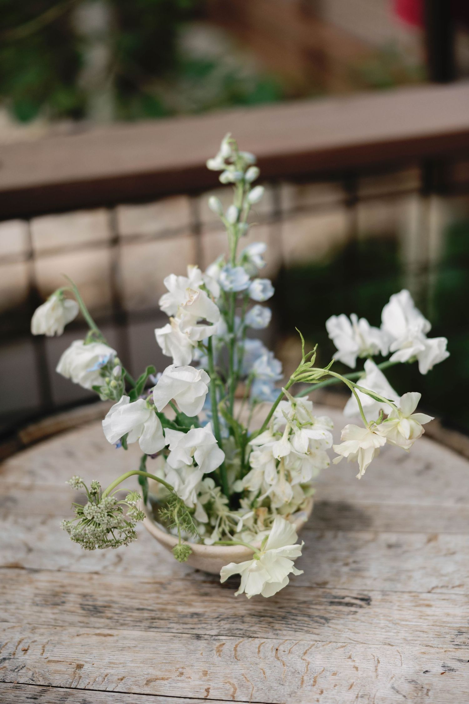 Delicate white and blue floral arrangements laid out on a rustic wooden surface.