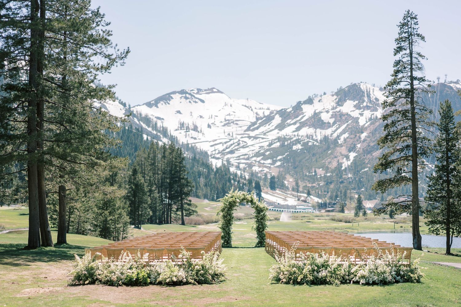 Mountain wedding ceremony site with floral arch and aisle decorations against snow-capped peaks at everline resort in lake tahoe,