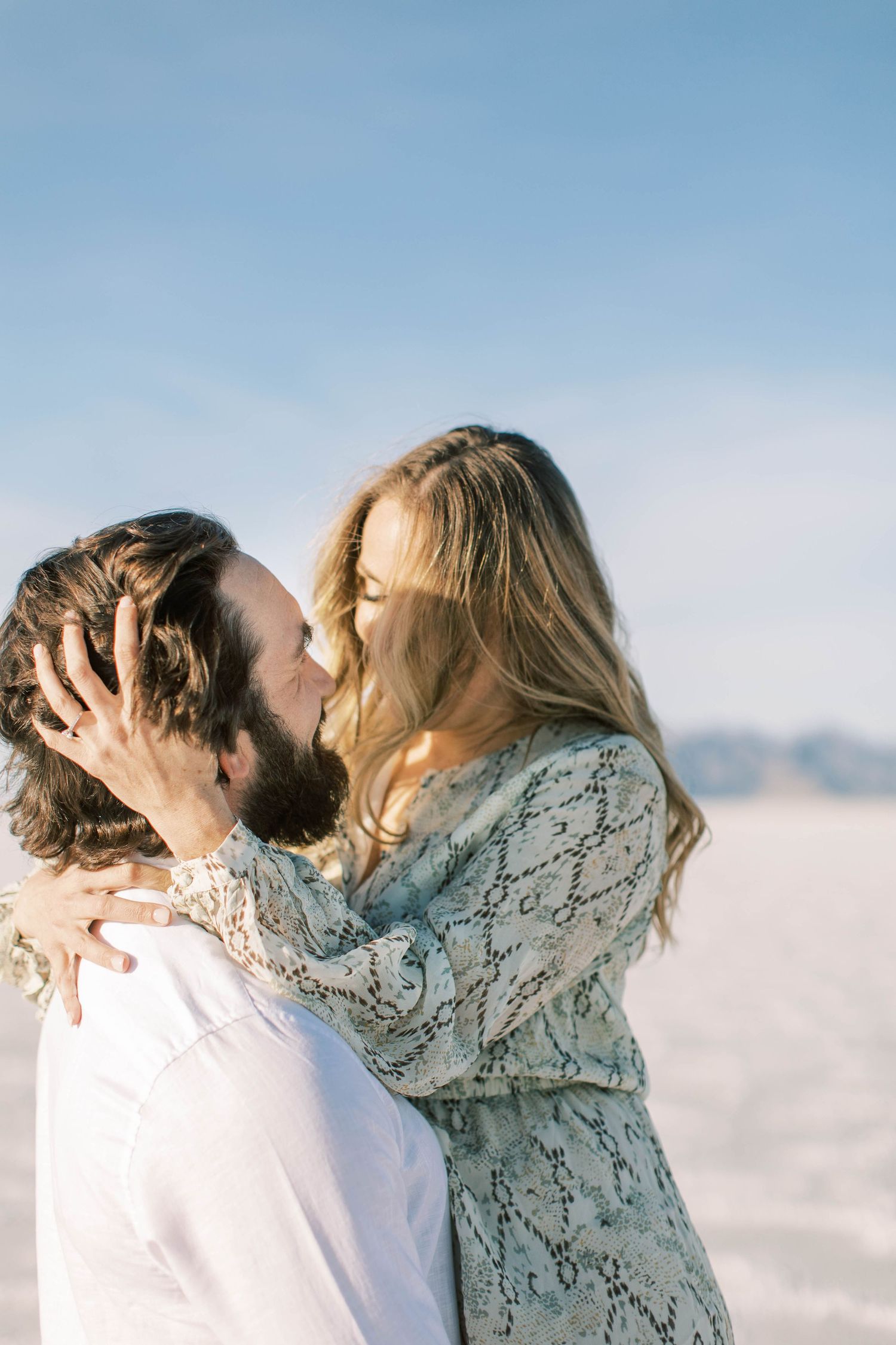 A romantic couple sharing an intimate moment on the Utah salt flats with mountains in the background.