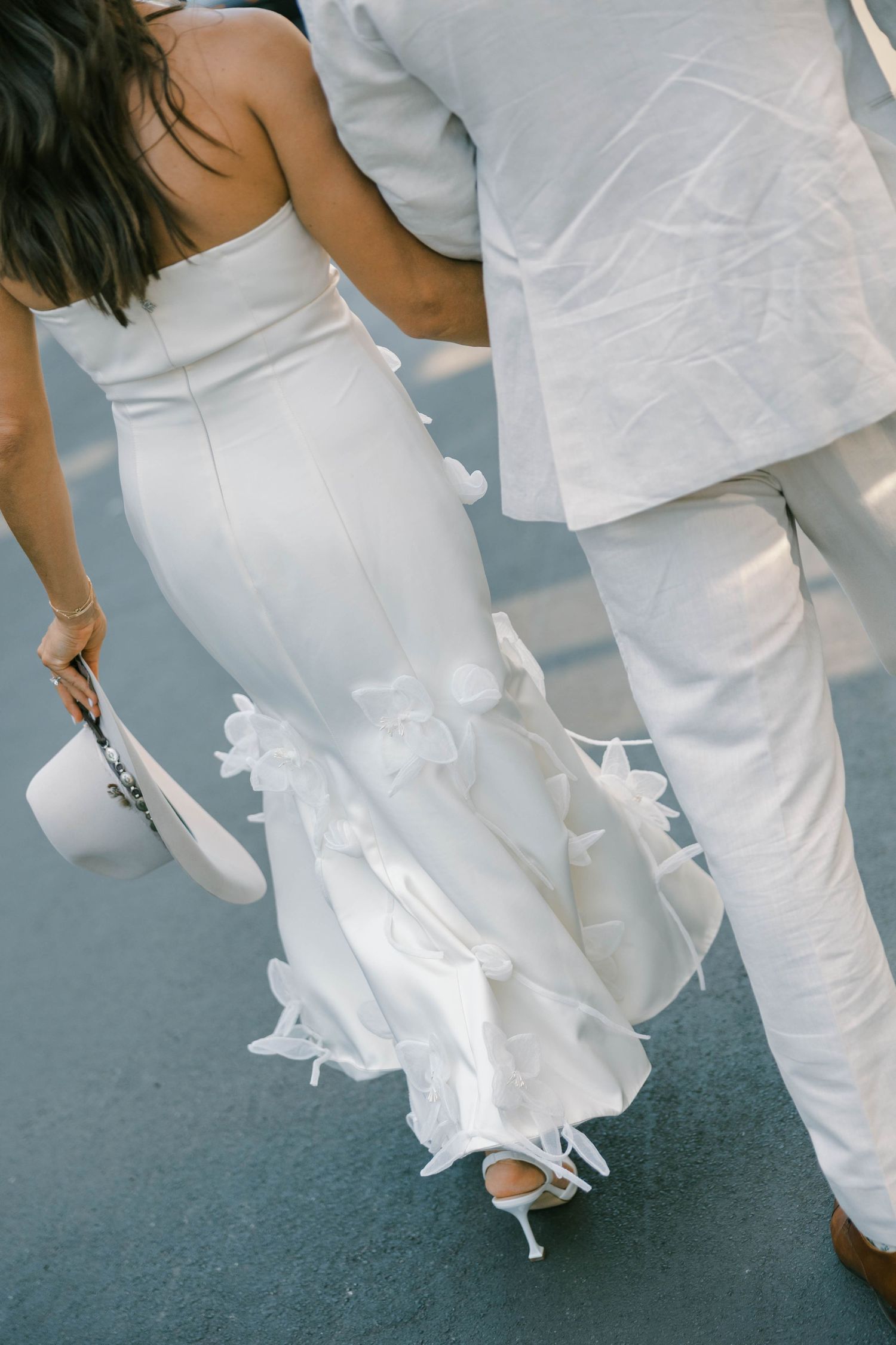 A series of photos showing the flowing movement of a white wedding dress and pants against a gray background.