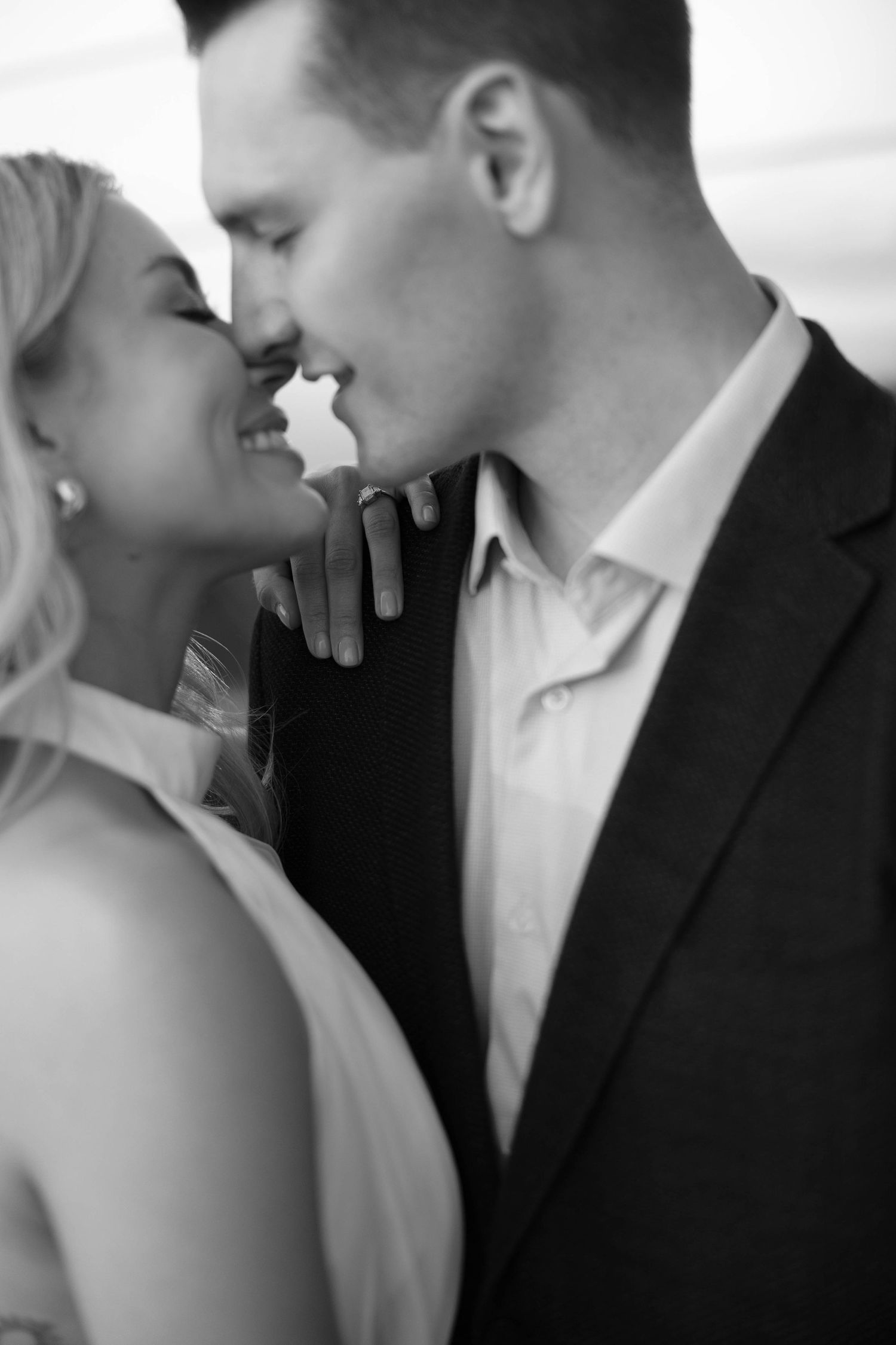 Intimate black and white portrait of a romantic couple in formal attire about to kiss.