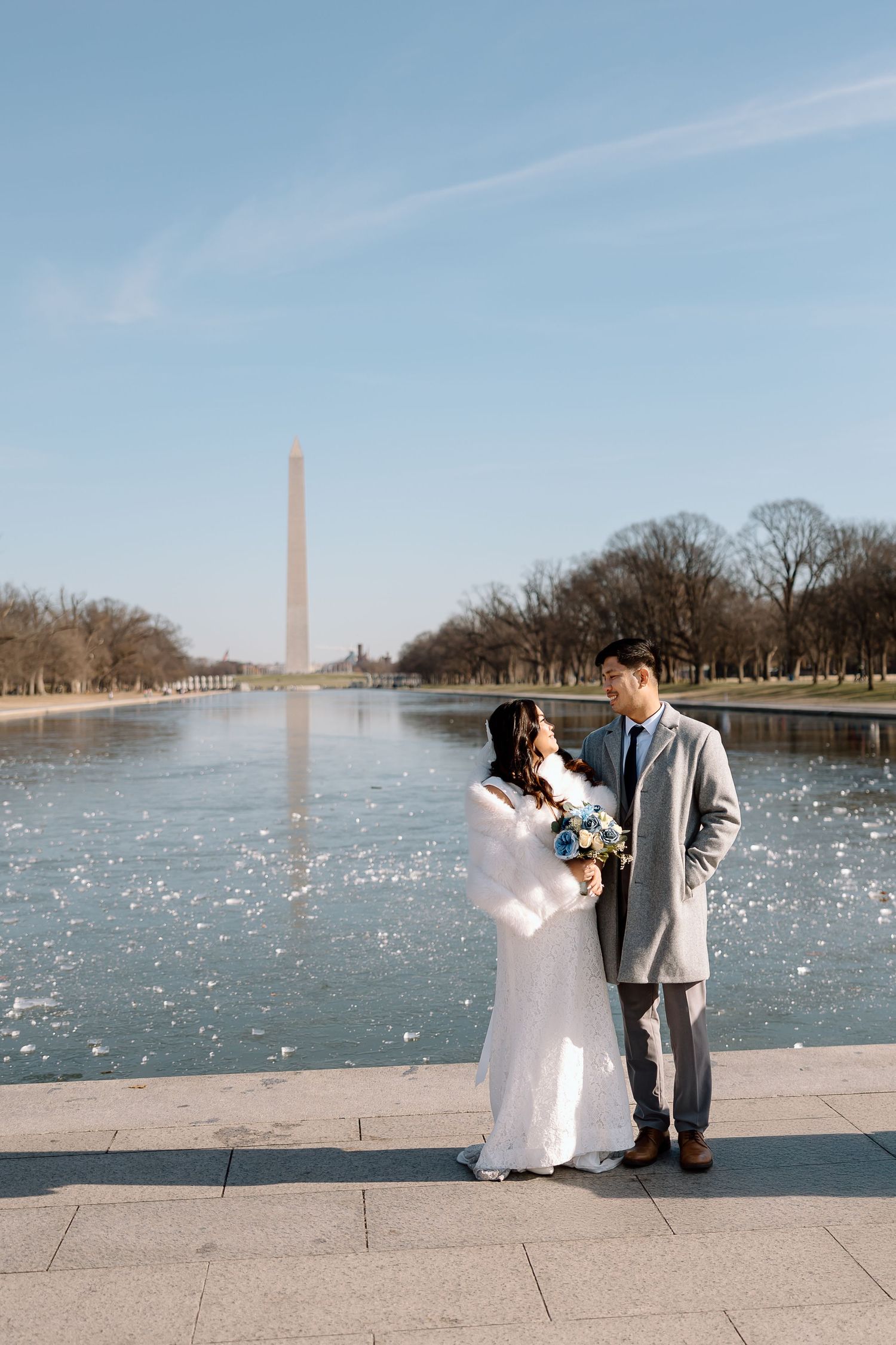 Bride and groom walking hand in hand along the Reflecting Pool during their DC elopemen