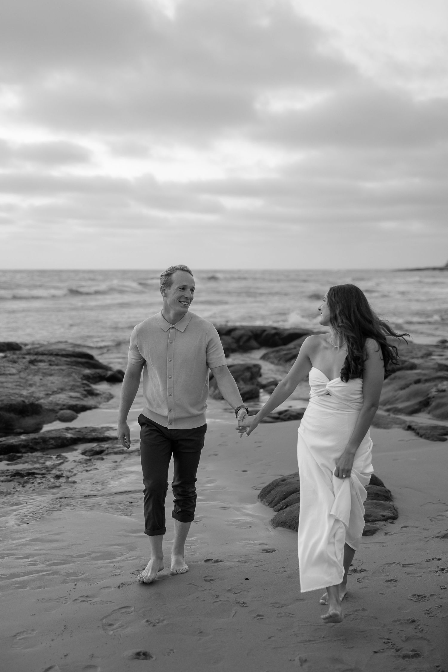 Couple walking along the shoreline at North Beach, Maryland during a sunset engagement session.