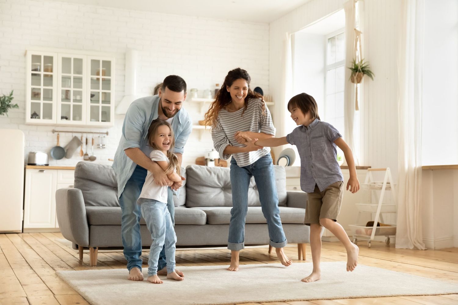 Happy family with two children dancing and playing together in a bright modern living room.