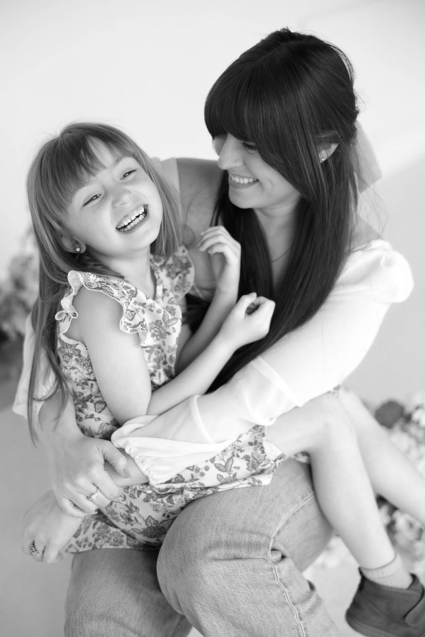 Black and white photo of smiling mother holding laughing young daughter indoors.