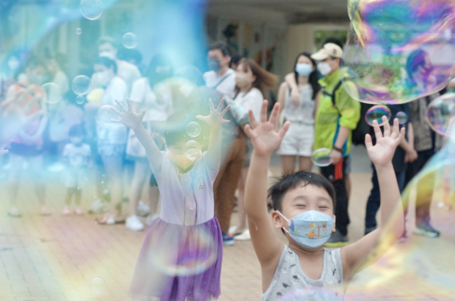 Colorful soap bubbles floating in the air at an outdoor gathering.