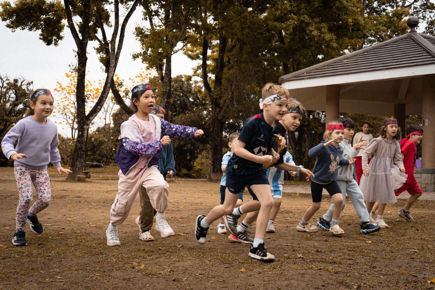 Children running and playing energetically during outdoor group activity in fall setting.