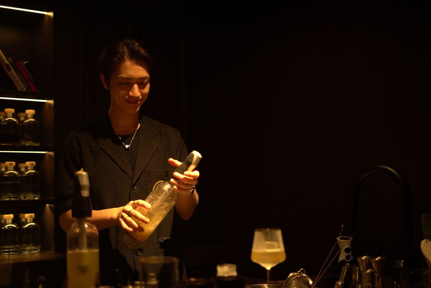 Bar staff examining bottle in moody lighting at upscale establishment.