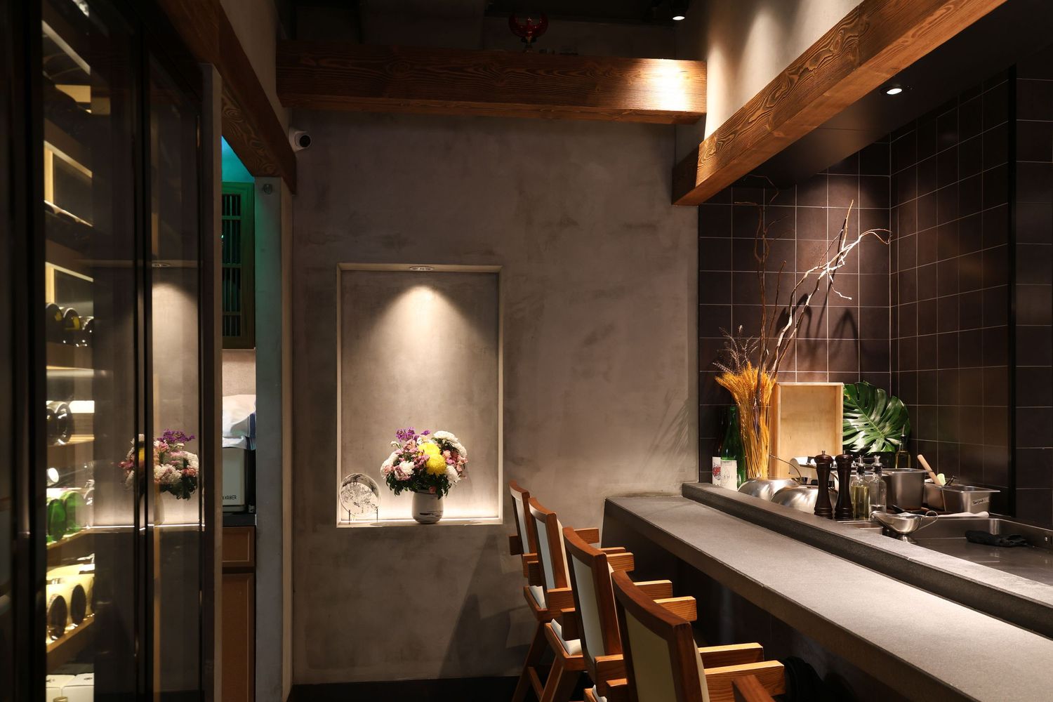 Modern restaurant interior with wooden bar seating, exposed beams, and dim ambient lighting creating an intimate atmosphere.