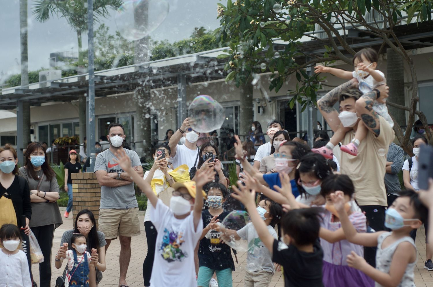 Crowd gathered outdoors watching soap bubbles float through the air.
