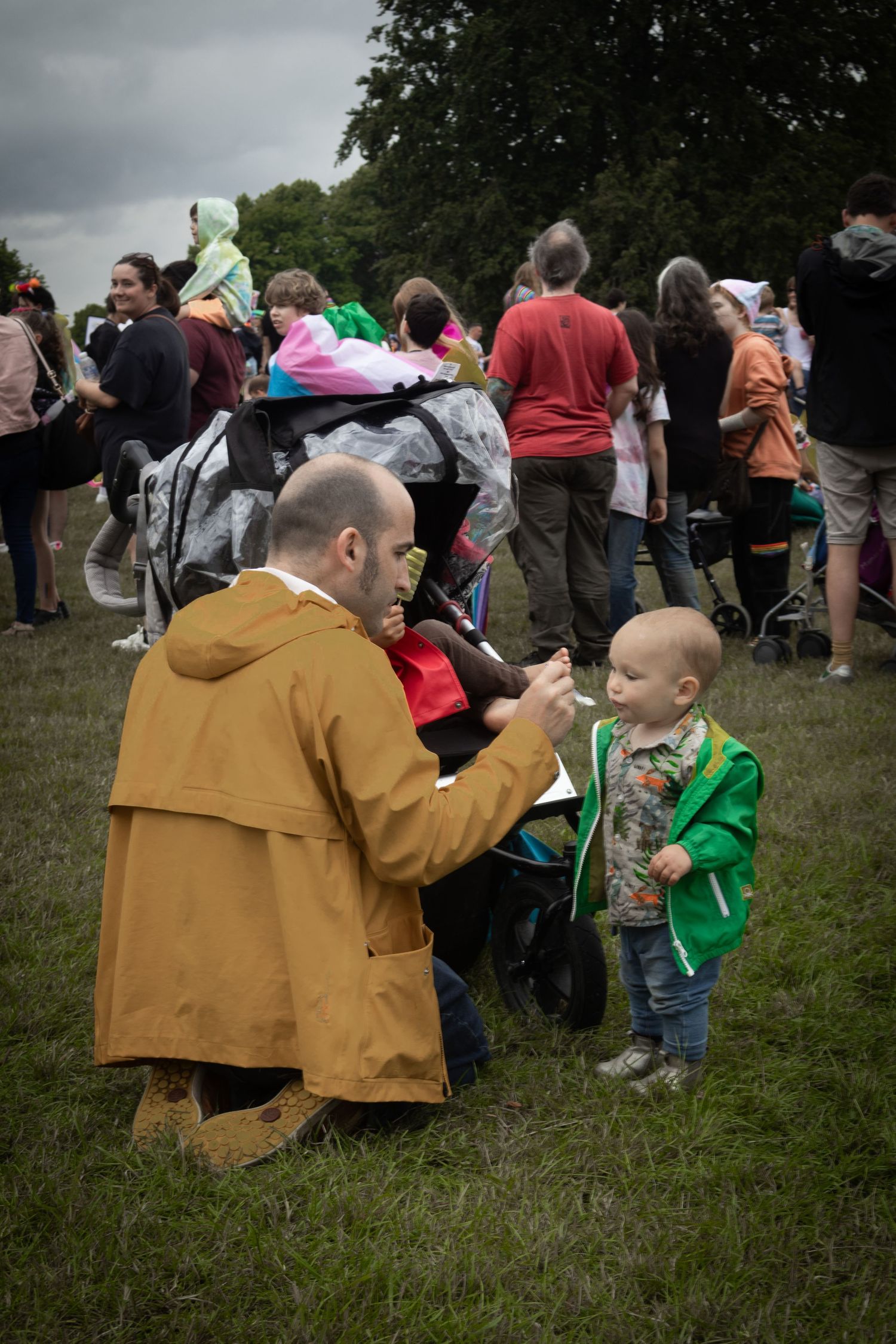People gather outdoors at a community event with families on a cloudy day.