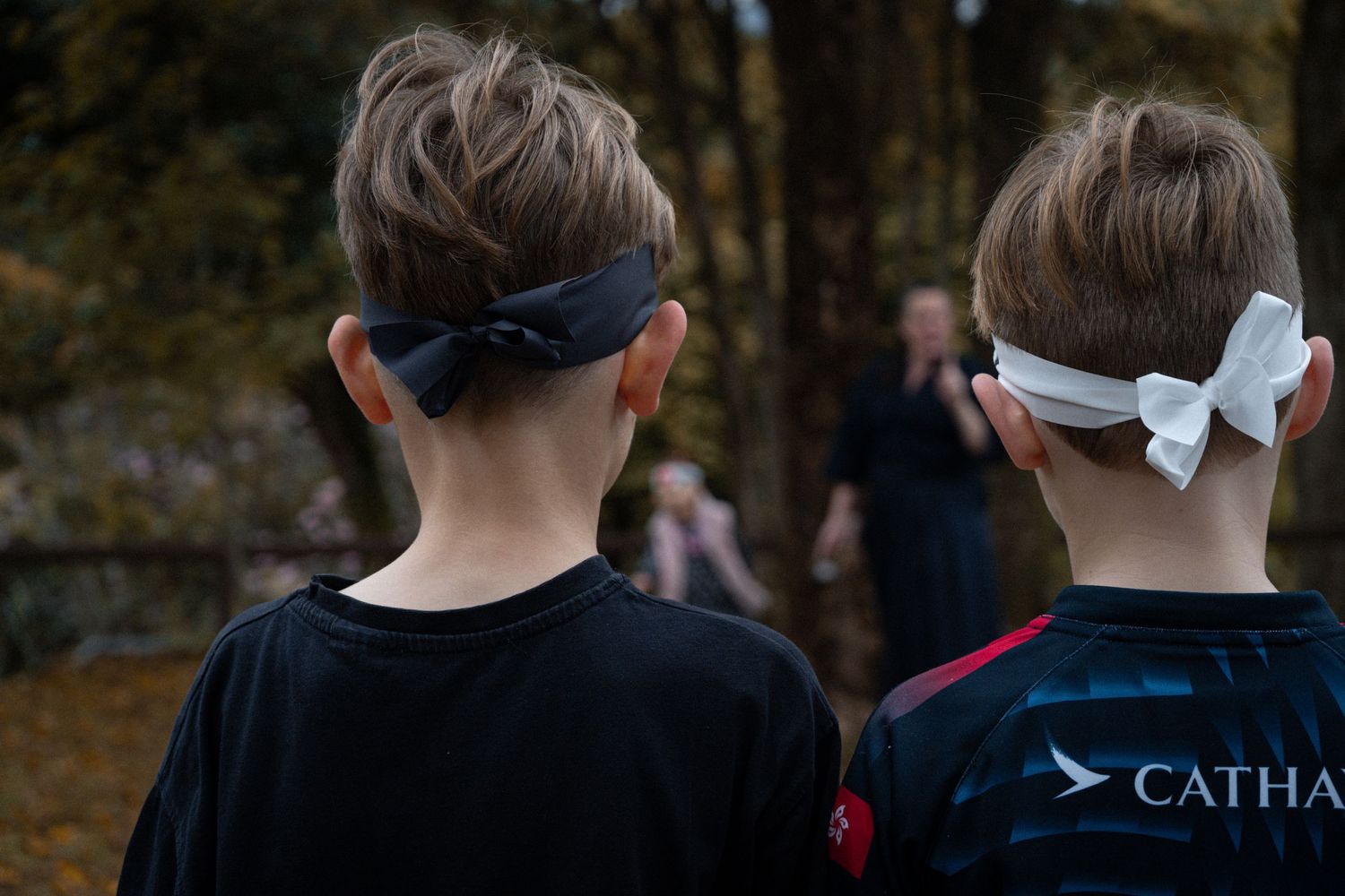 Two people wearing hair accessories viewed from behind during an outdoor event.