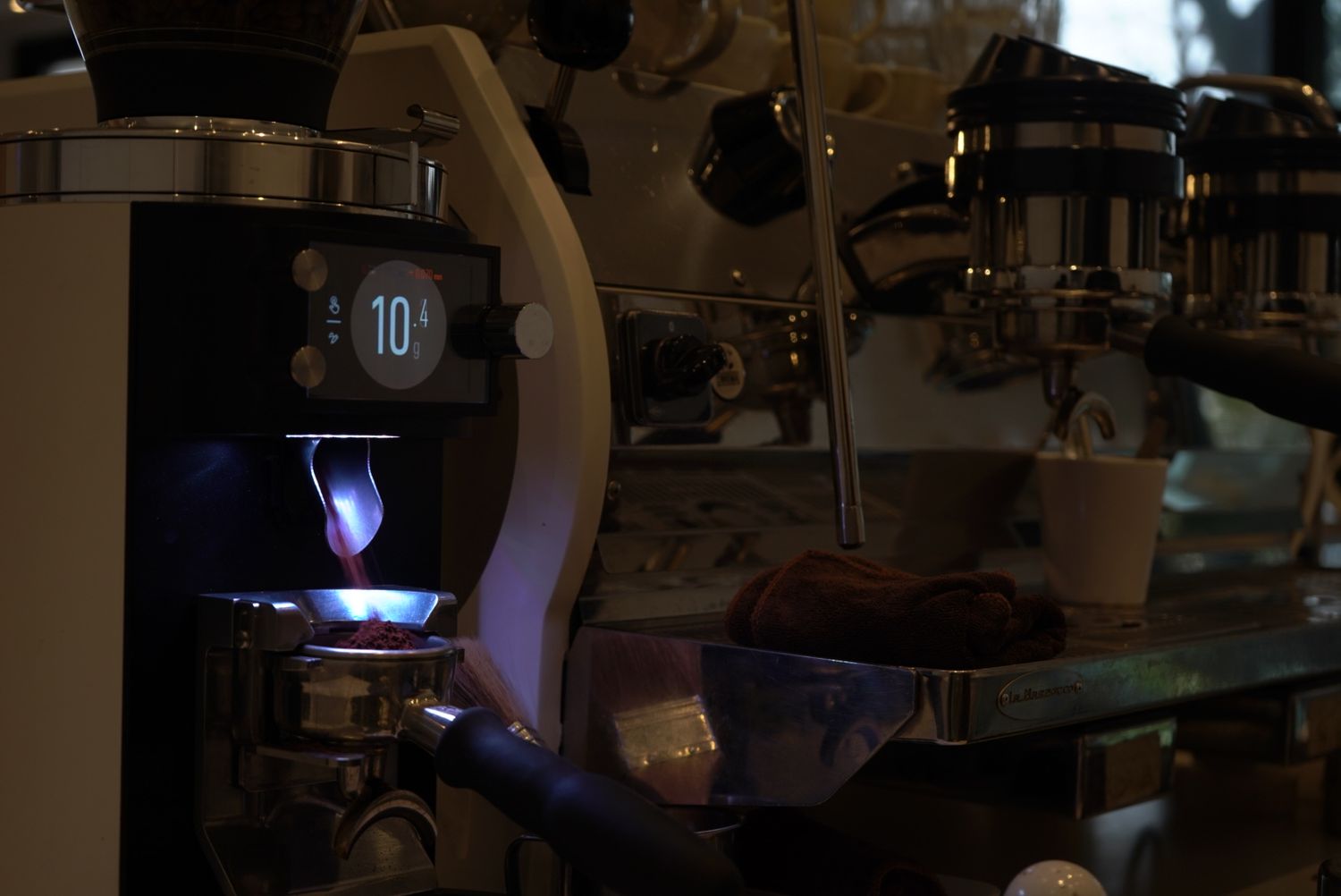 Coffee machine with illuminated blue light brewing espresso in dark environment.