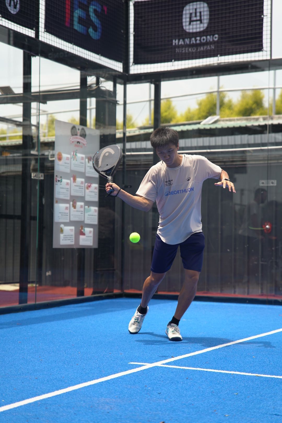 Player making a return shot on an outdoor blue padel court during daytime play.