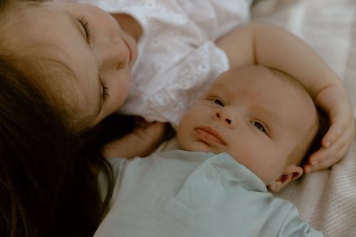 Gentle close-up portrait showing tender moment on white bedding.