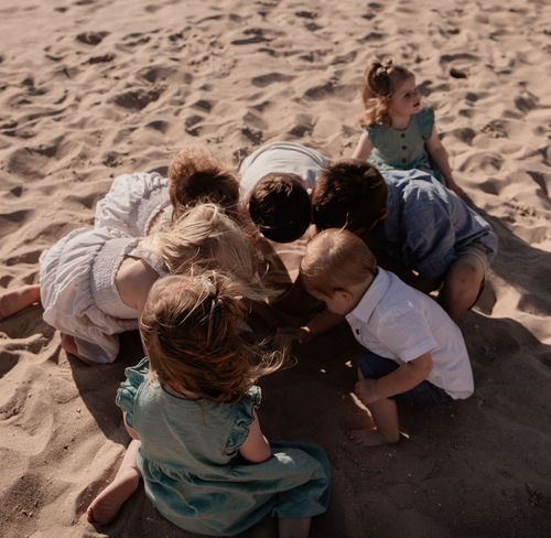 A group huddled together on beach sand creating an intimate moment.