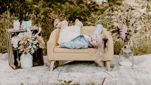 Dreamy outdoor photo with beige loveseat surrounded by wildflowers and greenery.