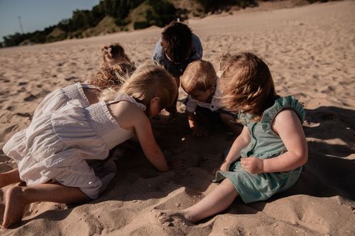A group gathered closely together on beach sand during a sunny day.