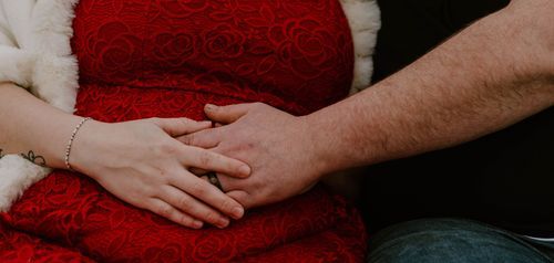 Two hands touching tenderly against red fabric background.