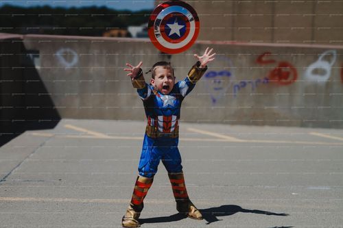 Young superhero enthusiast tosses Captain America shield while playing outdoors.