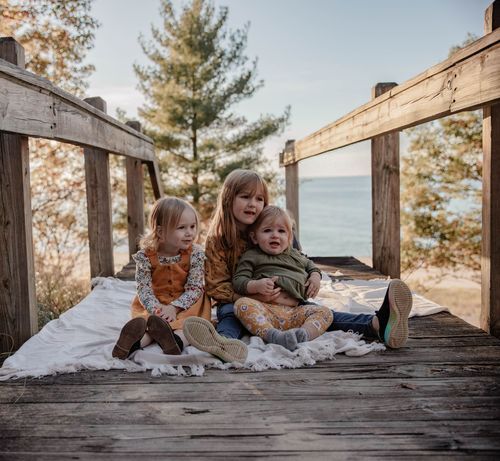 Family sitting together on snowy wooden observation deck with winter view.
