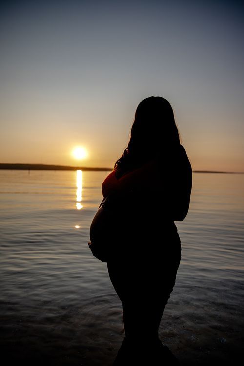Silhouetted figure against stunning sunset over calm water.