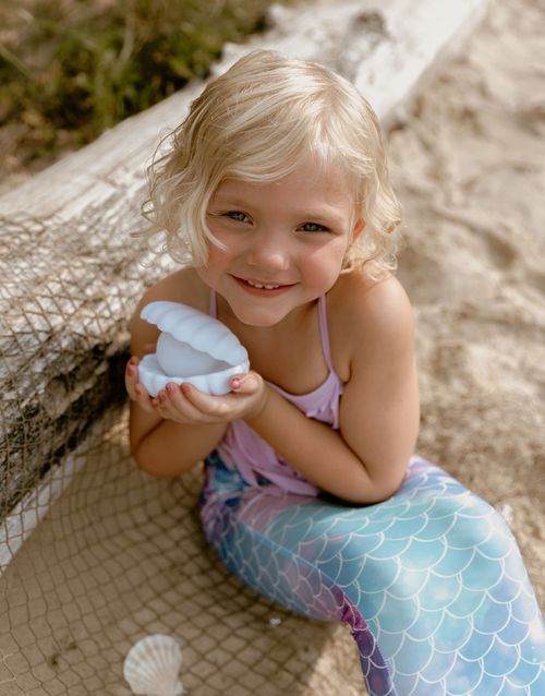 Magical beach scene with mermaid tail costume and seashell props.
