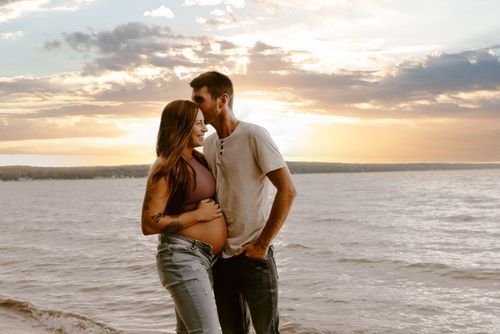 Intimate couple portrait against dramatic beach sunset sky.