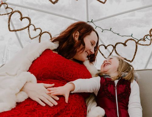 Candid moment of laughter shared under decorative heart garland backdrop.