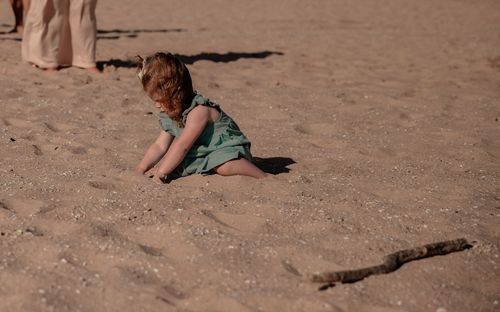 A child playing in red sand on a sunny day.