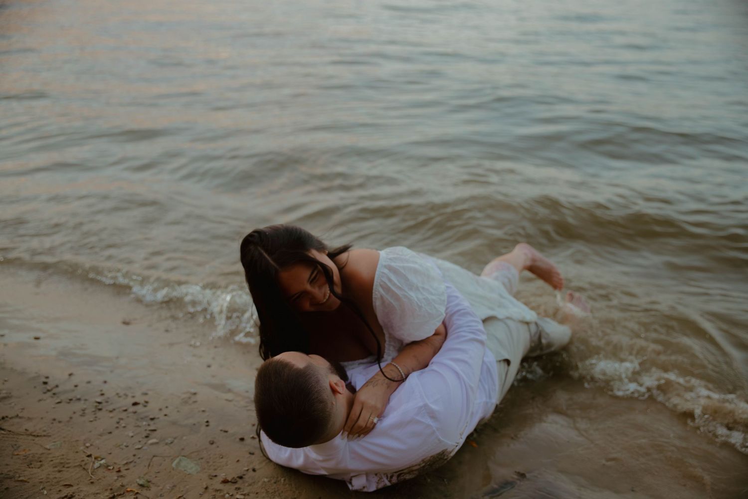 A couple shares an intimate moment at the water's edge during a romantic photoshoot.