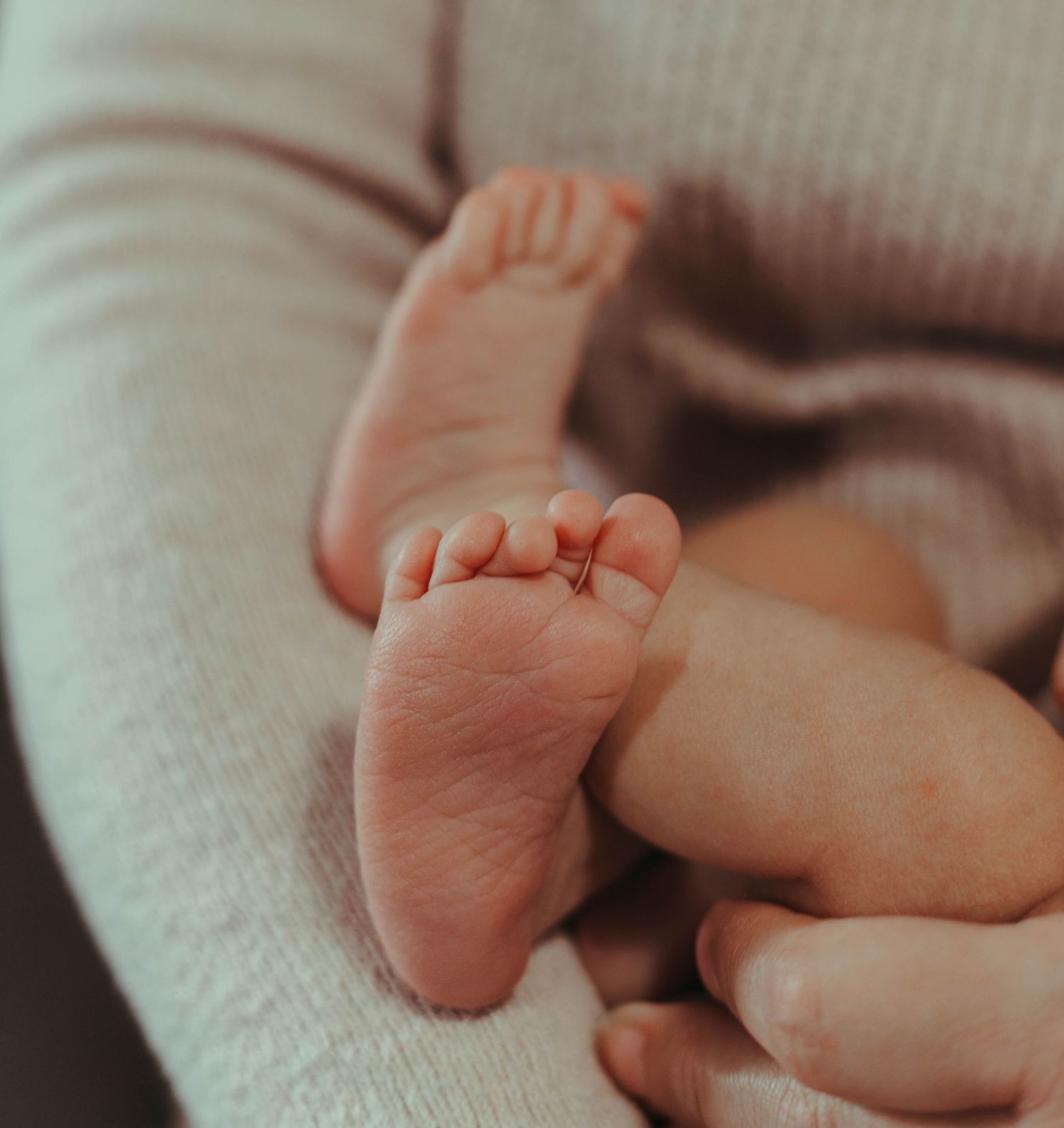 Close-up view of tiny newborn baby feet resting on a knitted blanket.