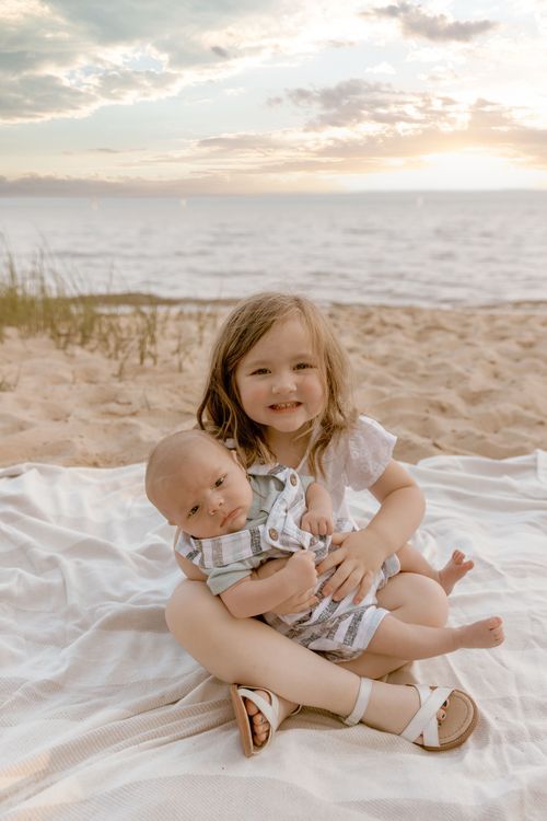 Heartwarming sunset beach portrait with white blanket and ocean waves in background.
