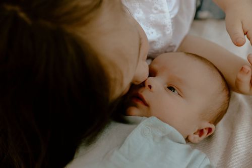 Intimate close-up portrait showing tender moment against white background.