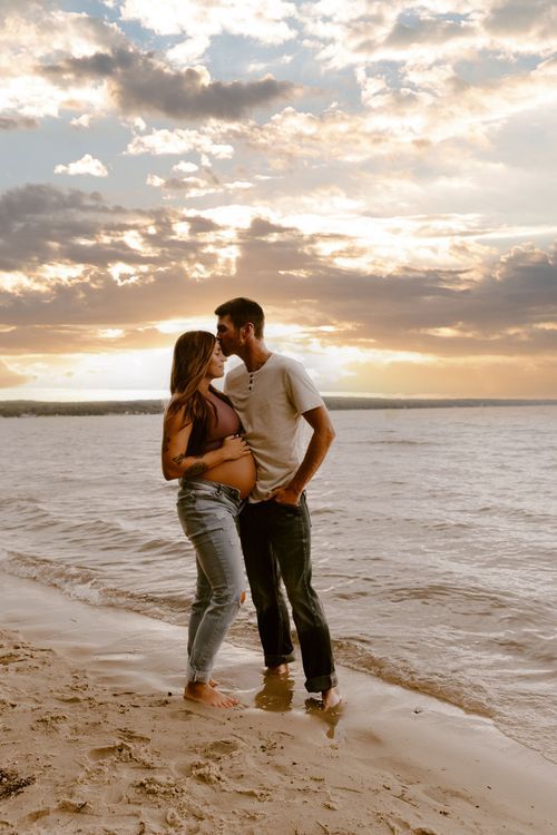 Romantic couple embracing on beach at golden hour sunset.